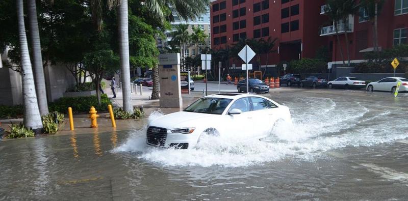 Car driving through water on street in a downtown scene
